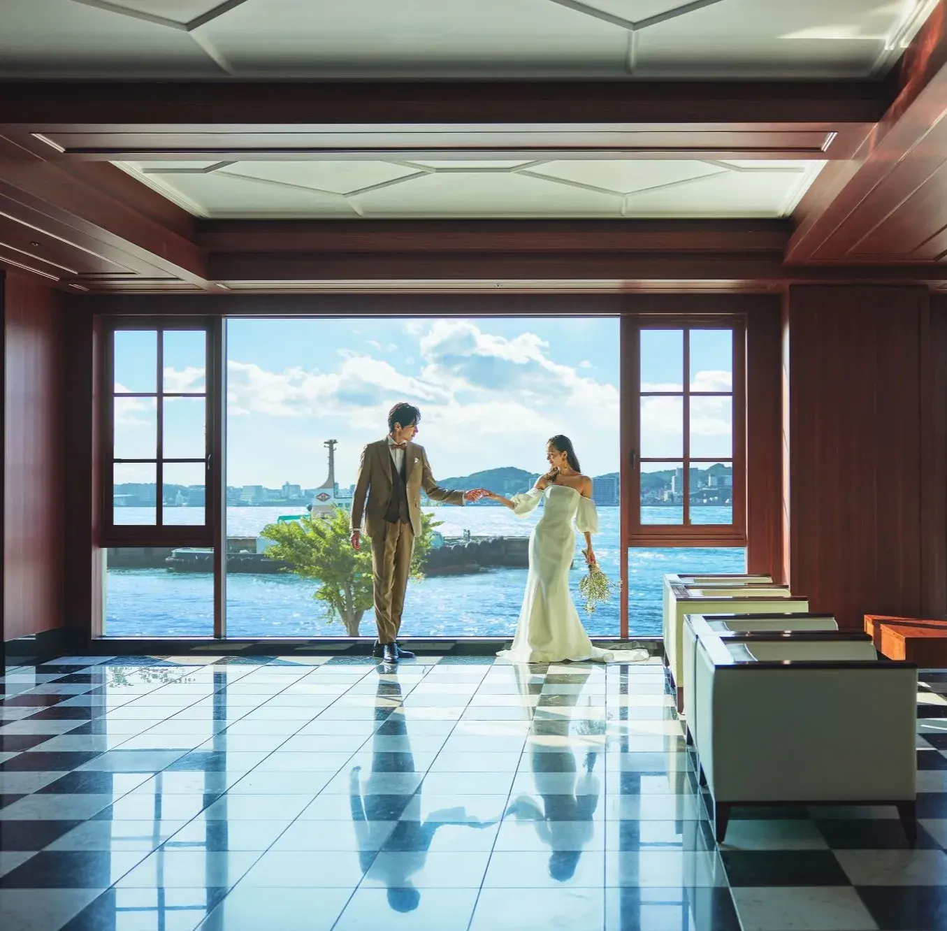 大きな窓から海を望む新郎新婦